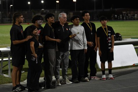 Cross country team and coach receiving medals at the Homecoming Game.